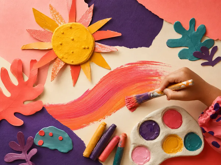 A child painting a bold colourful brushstroke among handmade art materials