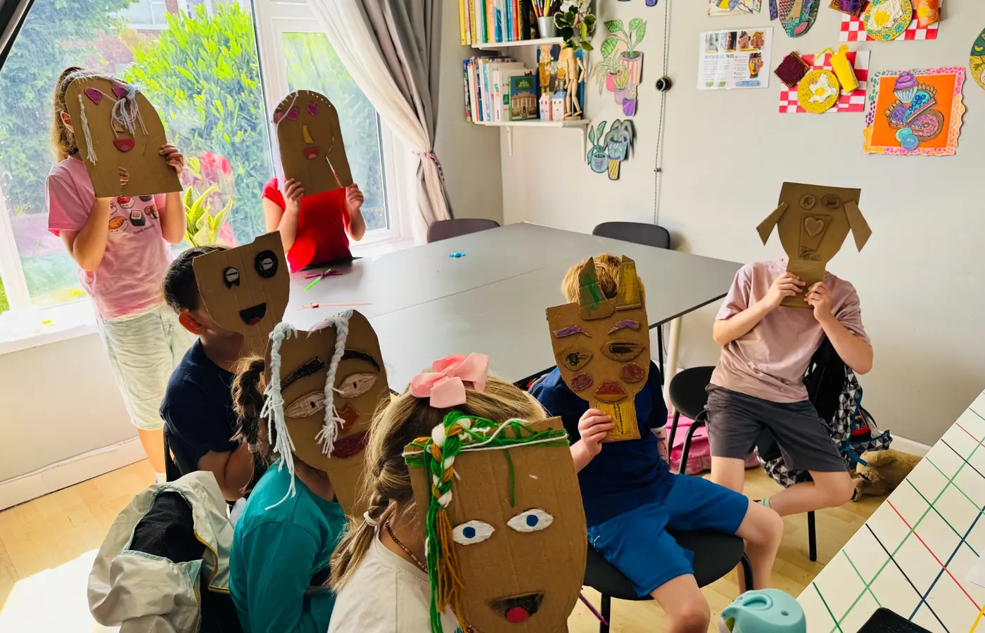 Children presenting their handmade cardboard portrait masks