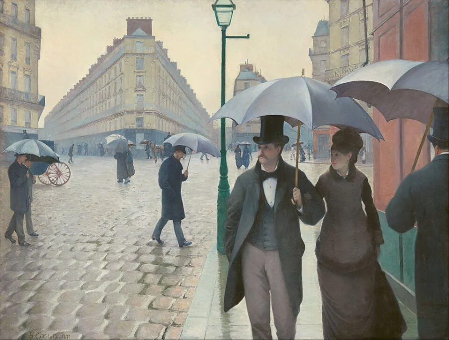People with umbrellas crossing a wet cobbled crossroads in a new part of Paris. Nothing historical or heroic is happening.